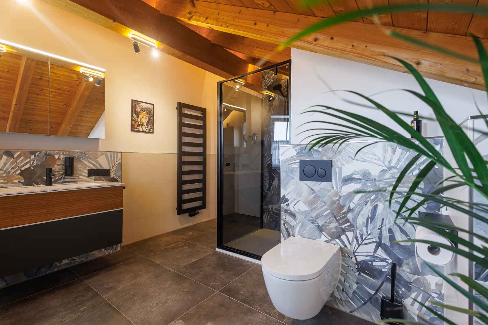 Saniertes Bad unter einer Holzdecke mit Waschtisch, Spiegelband und Dusche hinter Glas