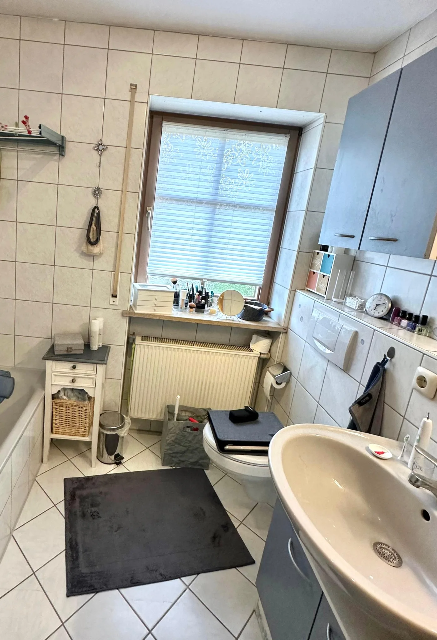 Altes Bad mit Badewanne, weißen Fliesen und Hängeschränken